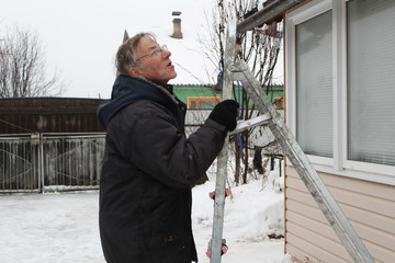 an elderly man climbed up the ladder.the pensioner wants to repair the roof of the porch at the house.