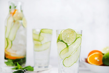 Homemade cold lemonade with lemon, lime, cucumber and mint on a white background.