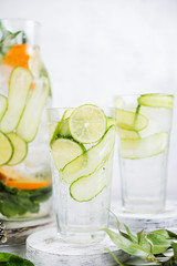 Homemade cold lemonade with lemon, lime, cucumber and mint on a white background.