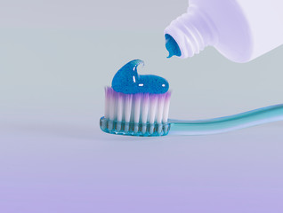 Toothpaste being squeezed onto a toothbrush. Purple gradient background