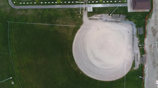 Aerial Over Highschool Sports Baseball Diamond With Several Players Practising And Parking Lot