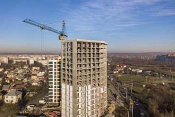 Fototapeta premium Aerial view of concrete frame of tall apartment building under construction in a city.