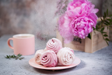 Homemade berry marshmallow in a plate is on the table with a Cup of tea. Powdered sugar falls on top of marshmallows..