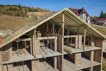 Wooden frame of new roof on a brick big house under construction.