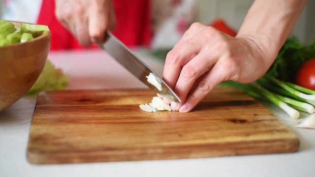 Chopping garlic on wooden board. Cooking soup