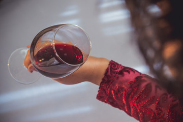 glass of red wine held by a woman's hand on white background