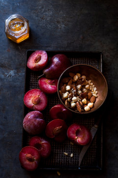 Plums Pears sliced with bowl of nuts honey on tray
