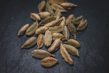 Macro view of green cardamom seeds in black slate background. 