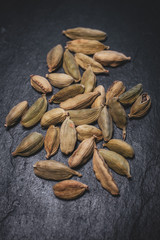 Macro view of green cardamom seeds in black slate background. 