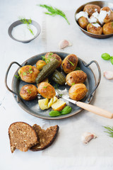 Classic Russian dish baked potatoes with sour cream and herbs and pickles. Vertical photo.