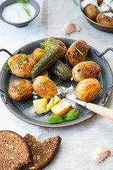 Classic Russian dish baked potatoes with sour cream and herbs and pickles. Vertical photo.