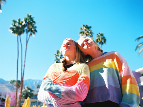 Teenage girls in rainbow striped sweaters standing outdoors