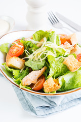 Caesar salad with chicken breast, tomatoes and wheat croutons in a plate on a white background. Vertical photo.