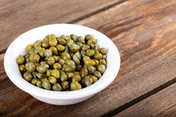 Okra seeds in white bowl on wooden background.