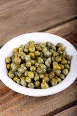 Okra seeds in white bowl on wooden background.