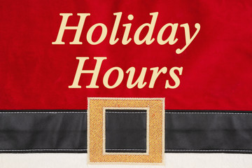 Fototapeta na wymiar Holiday Hours message on red and black Santa suit