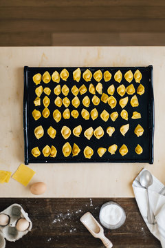 Freshly made italian stuffed ravioli pasta called cappelletti collected on tray on kitchen table