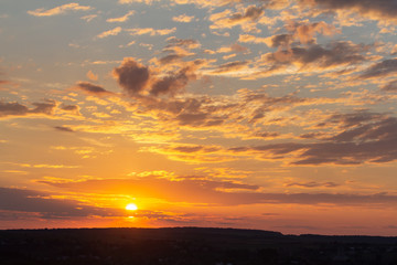Sunset sky covered with orange puffy clouds in the evening.