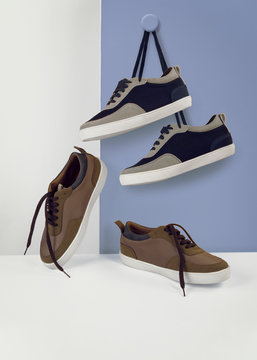 set of sneakers shoes hanging on blue and white background side and front view mood shot