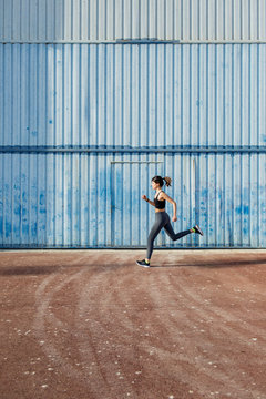 Young runner passing in front of a big blue metal door