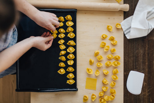 Unrecognozable woman collecting homemade cappelletti on tray seen from above