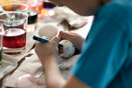 Boy Uses Crayon To Draw On Easter Egg