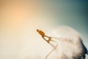 Silhouette image of a man showing the fly board (Aqua board) at sea ; The new spectacular sport