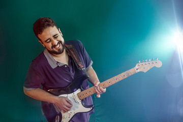 Obraz premium Rock. Music instrument Bearded man with electric guitar. latin man with electric guitar and green light in the background