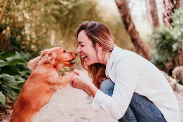 young woman and her cute puppy of cocker spaniel outdoors in a park