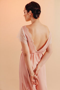Back view portrait of young woman with bun hairstyle wearing stylish clothes