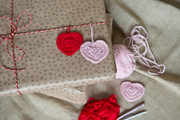 Gift boxes wrapped in craft paper, twine and knitted hearts. Modern presents for any holiday, christmas, valentine day or birthday/Close up/ Top view