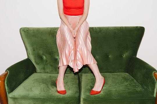 Woman With Pink Pleated Skirt On Green Velvet Couch