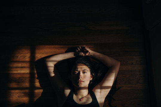 Portrait of woman looking serious at the camera with arms above head
