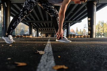 Crop sportswoman stretching on sports ground