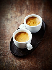 Two cups of coffee on rustic background. 