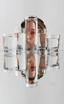 Portrait of woman wearing sunglasses distorted through glasses with water