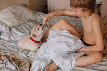 Boy with varicella playing with puppet on the bed
