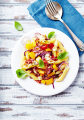 Penne Pasta with red onion, mozzarella cheese, yellow pepper and fresh herbs. White wooden background. Top view.