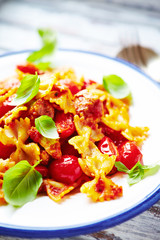 Farfalle pasta with cherry tomatoes, chicken breast and fresh basil. Close up.