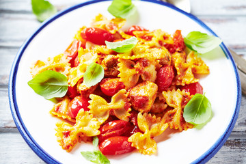 Farfalle pasta with cherry tomatoes, chicken breast and fresh basil. Close up.
