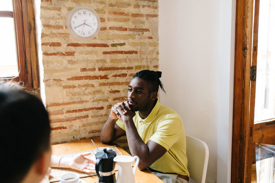 African American man sitting at table with hot drinks with frien