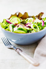 Healthy Salad with Green Olives, Cucumber, Red Onion and Lettuce. Easy summer snack. Bright wooden background. 