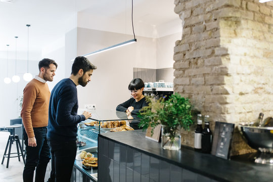 Cheerful barista serving costumers in cafe