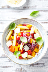 Penne pasta with yellow and red pepper, hard cheese and fresh basil.  Bright background. Top view. 