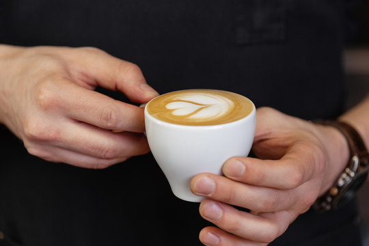 Crop man holding cup with latte