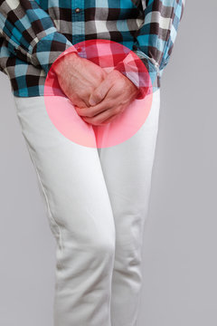 Concept of male sexual diseases. The man holds hands for genitals. Testicular cancer. A red circle, like a hotbed of disease