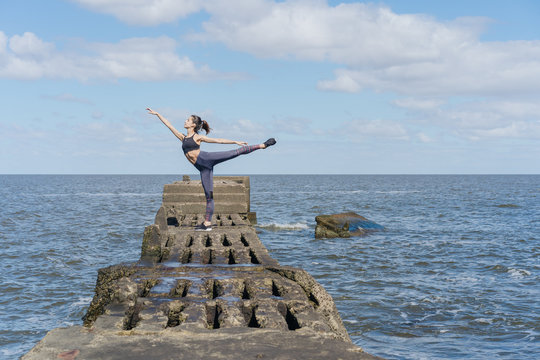 Flexible And Fit Young Woman Practicing Pilates By The Seaside.
