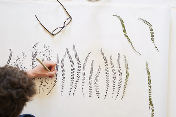 Artist drawing leaves patterns on paper