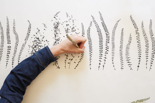 Artist drawing leaves patterns on paper