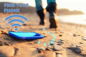 The concept of losing your phone. The smartphone lies on the sand, on the beach. In the background, blurred removing footsteps of a man. Inscription 